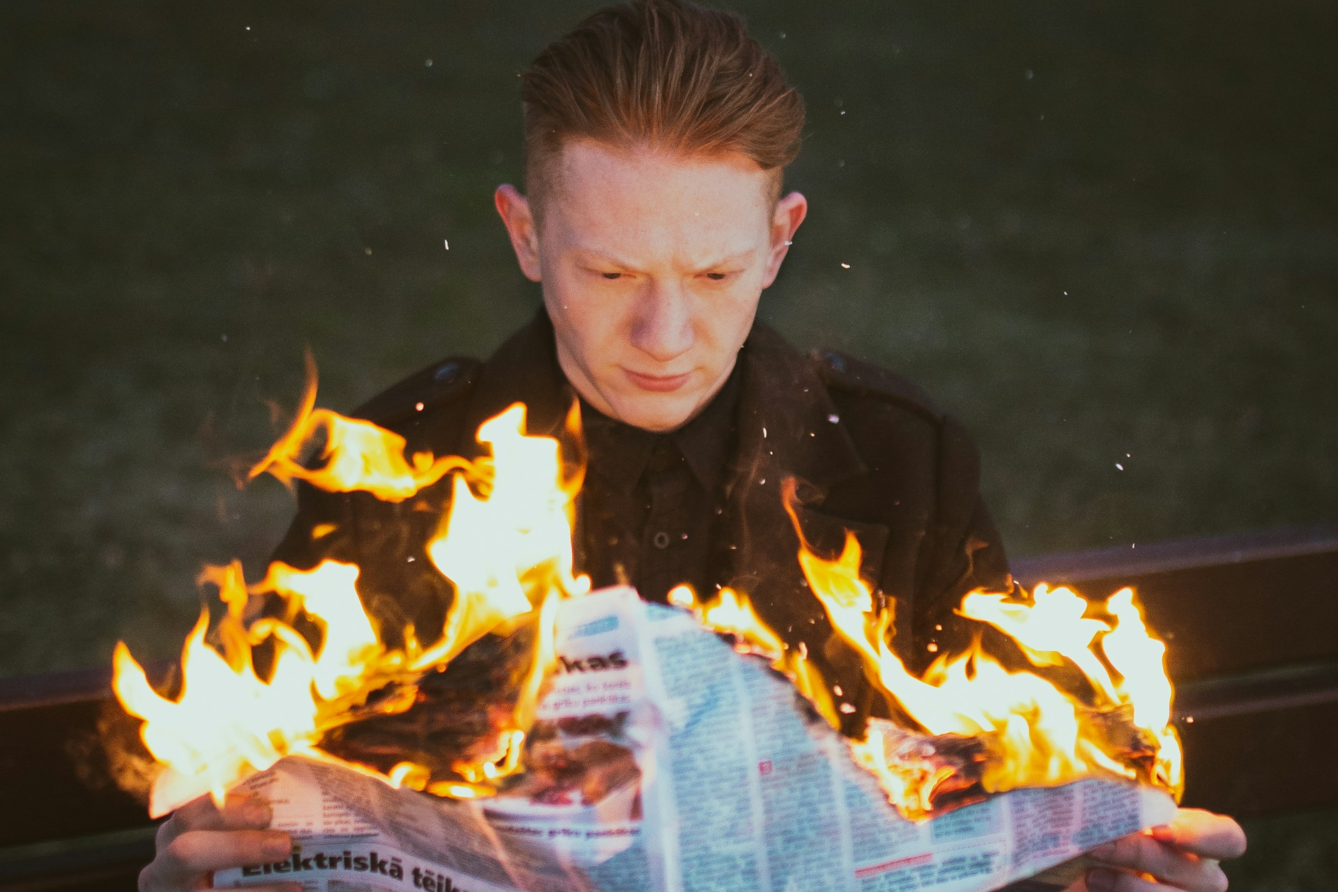 Man holding a burning newspaper
